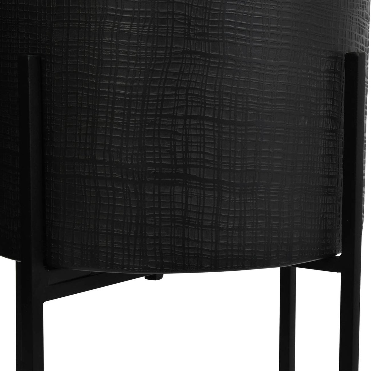 Close-up of Libra Interiors Etched Iron floor standing planter in matt black, showing the cross hatch textured cylindrical pot on slim four leg metal stand.