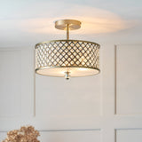 Endon Prescott 3 light crystal flush ceiling light in antique brass with drum shade and crystal lattice detailing, illuminated in a panelled room.