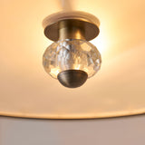 Close-up of Endon Prescott flush ceiling light showing a faceted crystal lamp holder with antique brass fittings against the glowing glass shade.