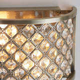 Close-up of the Endon Prescott antique brass wall light showing the crystal bead lattice and curved steel frame illuminated with a warm glow.