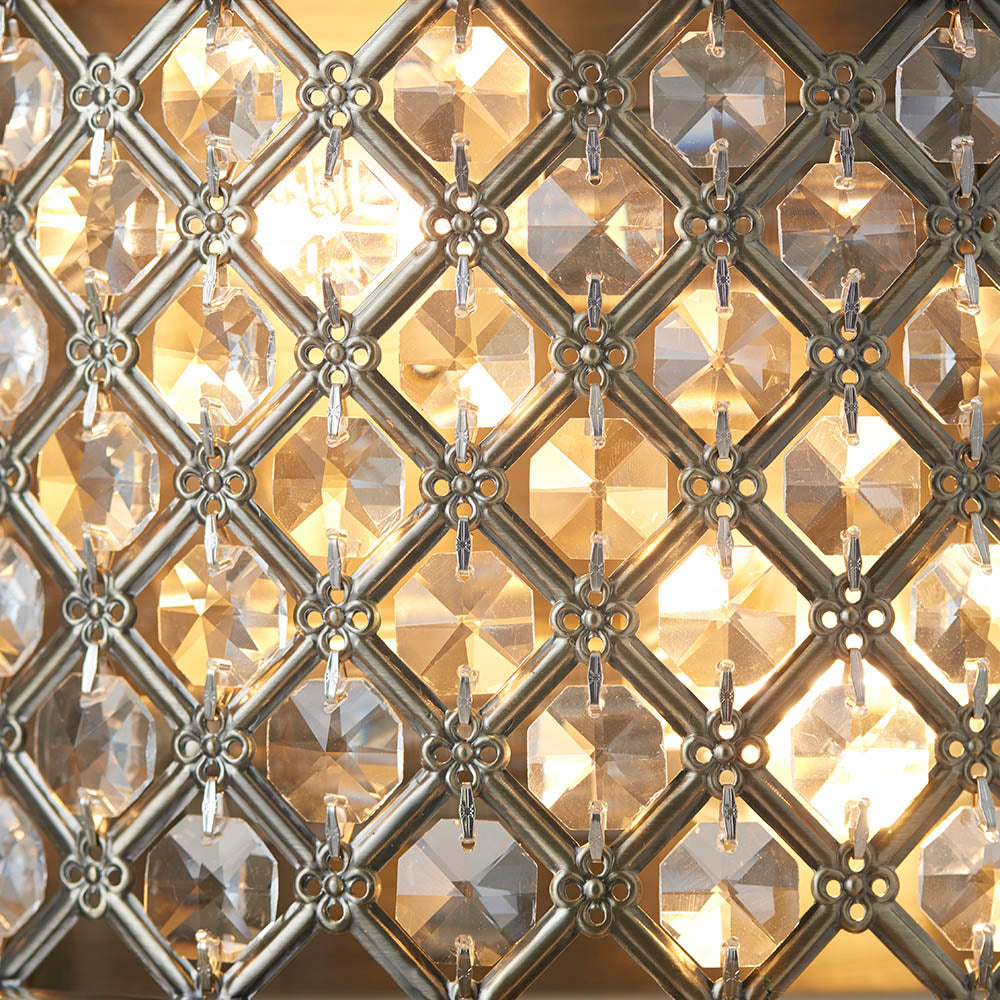 Close-up of Endon Prescott Wall Light in antique brass, showing the diamond-lattice steel frame set with clear crystal beads glowing warmly from the twin lamps.
