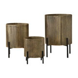 Libra Interiors Ribbed Iron Set of 3 Footed Planters in antique gold with ebony shading, graduated cylindrical bodies on slim black legs, on a white background.
