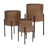 Libra Interiors Ribbed Iron Set of 3 Standing Planters in antique gold, cylindrical fluted bodies on tapered black iron legs, shown on a white background.