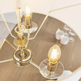 Close-up of Endon Castdon 3 Light Pendant in brass with K9 crystal bobeches and lit E14 candle bulbs, viewed above a wooden dining table.