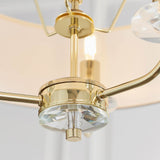 Close-up of the Endon Castdon 3 Light Pendant showing the brass central hub, K9 crystal bobeche detail, and edges of the white faux silk shades.