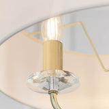 Close-up of Endon Castdon pendant showing a brass arm with lit E14 filament lamp, K9 crystal bobeche and edge of a vintage white faux silk shade.