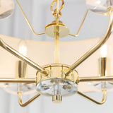 Close-up of the Endon Castdon 6 Light Pendant showing the polished brass arms, central K9 crystal detail, and chain suspension beneath white shades.
