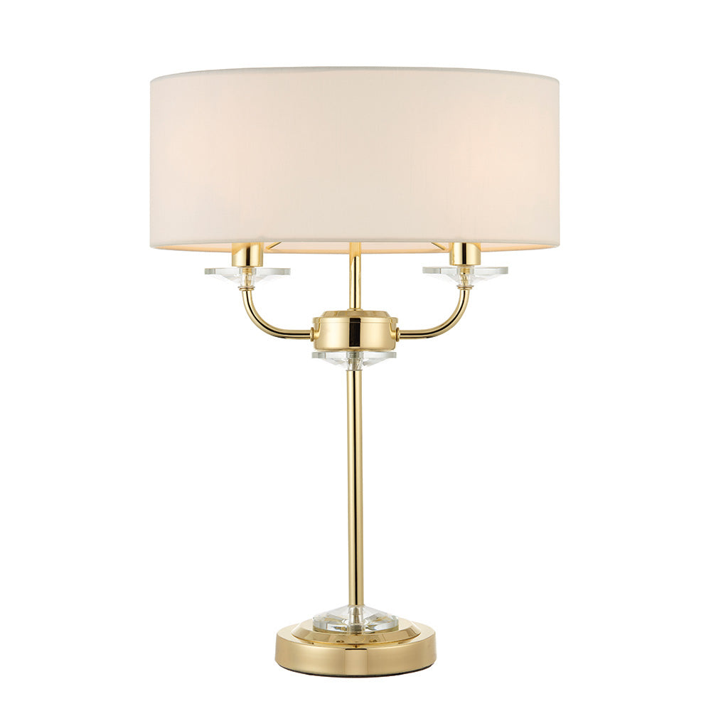 Castdon 2 Light Table Lamp with brass metal frame, crystal glass accents, and a white drum fabric shade, shown on a plain white background.