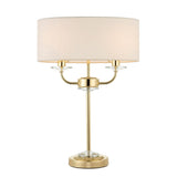 Castdon 2 Light Table Lamp with brass metal frame, crystal glass accents, and a white drum fabric shade, shown on a plain white background.