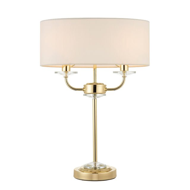 Castdon 2 Light Table Lamp with brass metal frame, crystal glass accents, and a white drum fabric shade, shown on a plain white background.