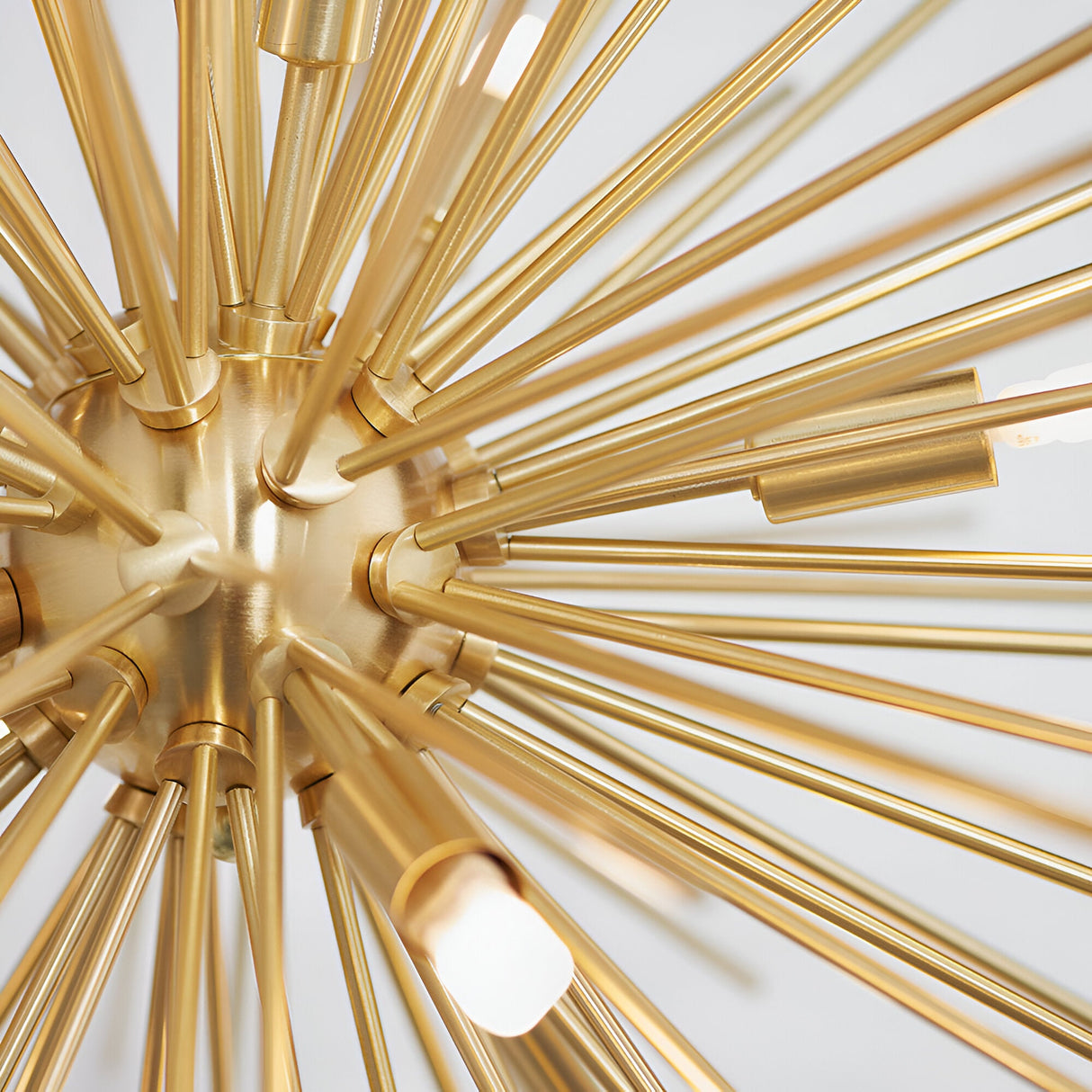 Close-up of the Merrick 9 Light Sputnik Pendant in satin brass, showing metal rods radiating from a central hub with G9 bulb tips, against a plain white background.
