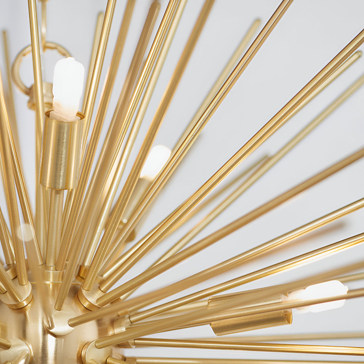 Close-up of the Merrick 9 Light Sputnik Pendant in satin brass, showing radiating metal rods with lit G9 bulbs against a plain white background.