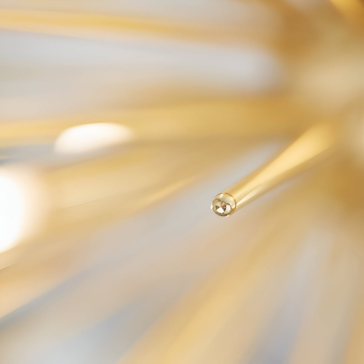 Close-up of the Merrick 9 Light Sputnik Pendant in satin brass, showing one rod tip with G9 bulb fitting against blurred radiating arms.