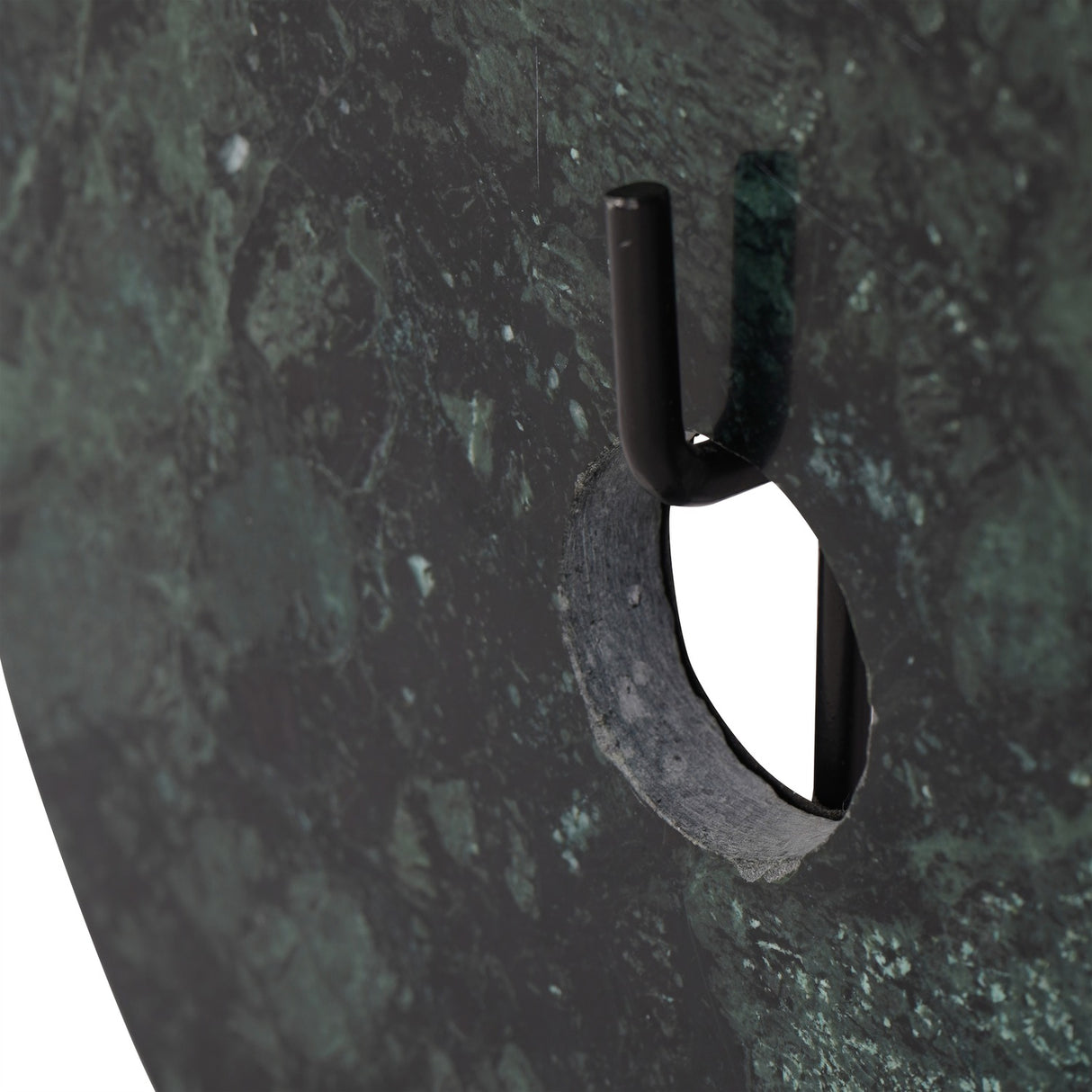 Close-up of Libra Interiors Green Marble Disc Sculpture showing the central opening, veined deep green marble surface and black iron stem support.