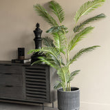Libra Interiors Faux Areca Palm 6ft in a ribbed grey planter beside a dark wood sideboard with a black chess king ornament and Monet book.