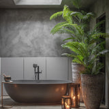 Libra Interiors Faux Areca Palm in tall textured stone-effect planters beside a matte black freestanding bath, candle lanterns and grey plaster walls.