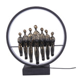 Libra Interiors Bronze Family Circle LED lighting accessory with seven antique bronze resin figures seated within a black metal ring on a plinth base.