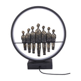 Libra Interiors Bronze Family Circle LED lighting accessory with seven antique bronze resin figures inside a black metal ring on a solid base.