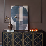 Libra Interiors Fretwork black mango wood sideboard styled in a moody interior with abstract geometric art, bronze vase and lit candles on top.