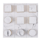 Libra Interiors Marble Effect noughts and crosses game shown top-down with square blocks and circular counters, white marble resin finish and brass-tone edging.