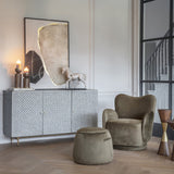 Libra Interiors Bingham green velvet swivel armchair with rounded back and curved arms, styled beside a patterned sideboard and matching footstool.