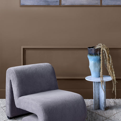 Libra Interiors Curved Corduroy Accent Armchair in grey ribbed cord with looped S-shaped base, styled beside a marble side table and blue ceramic vase.