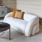 Libra Interiors Velvet Wraparound 2 Seater Sofa in cream with curved tiered arms, styled with mustard and tan cushions beside a black round coffee table.