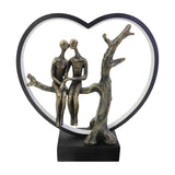 Libra Interiors Antique Bronze Couple LED lighting accessory with resin figures seated by a tree inside a black heart frame on a square base.