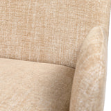Libra Interiors fully upholstered fabric carver dining chair in wheat beige, close-up showing textured woven back meeting a softly padded rounded arm.
