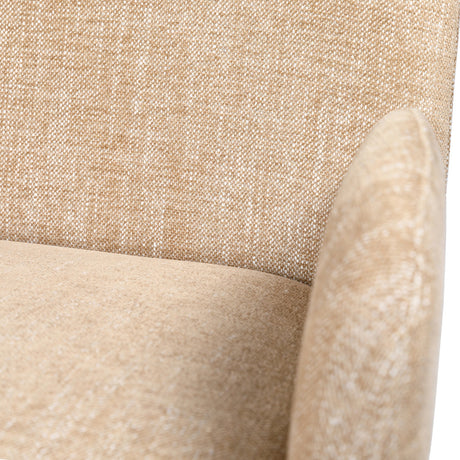 Libra Interiors fully upholstered fabric carver dining chair in wheat beige, close-up showing textured woven back meeting a softly padded rounded arm.