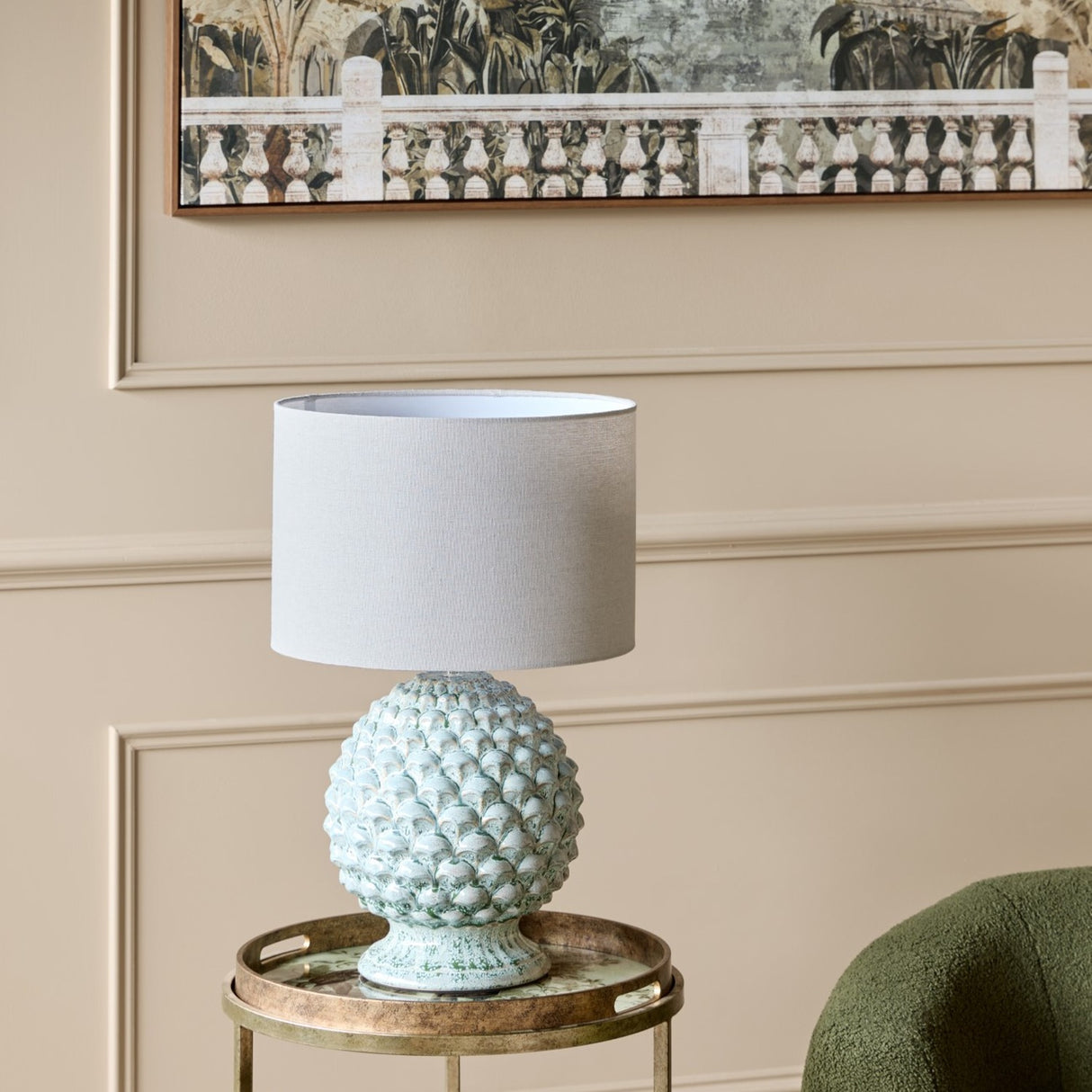 Libra Interiors Glazed Ceramic Artichoke table lamp in green with layered petal base and pale drum shade, on a gold tray table beneath framed botanical art.