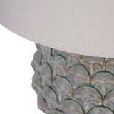 Close-up of Libra Interiors Glazed Ceramic Artichoke Table Lamp in green, showing the layered petal-moulded base with mottled glaze beneath a pale drum shade.