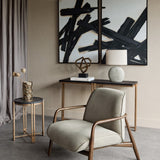 Libra Interiors textured grey ceramic oval table lamp with linen-look shade on a bronze console table, styled with abstract art, armchair and side table.