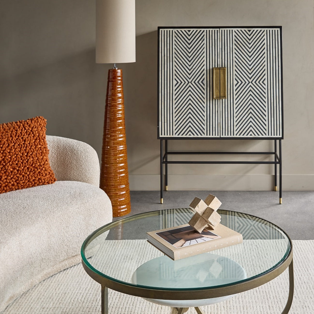 Libra Interiors Ribbed Ceramic Tapered Floor Lamp in terracotta with tall linen shade, styled beside a bouclé sofa, glass coffee table and patterned cabinet.