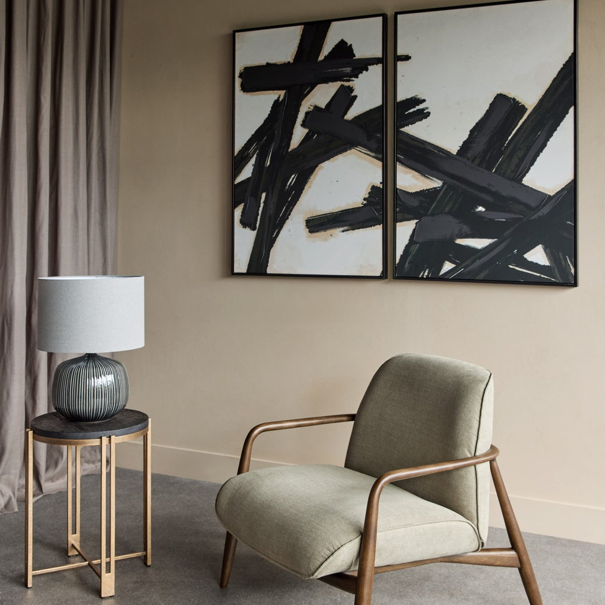 Libra Interiors Ribbed Ceramic Table Lamp in charcoal with grey fabric drum shade, on a bronze side table beside a linen armchair and abstract wall art.