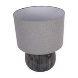 Libra Interiors Ribbed Ceramic Table Lamp in charcoal with a rounded ribbed glazed base and grey fabric drum shade, shown on a plain white background.
