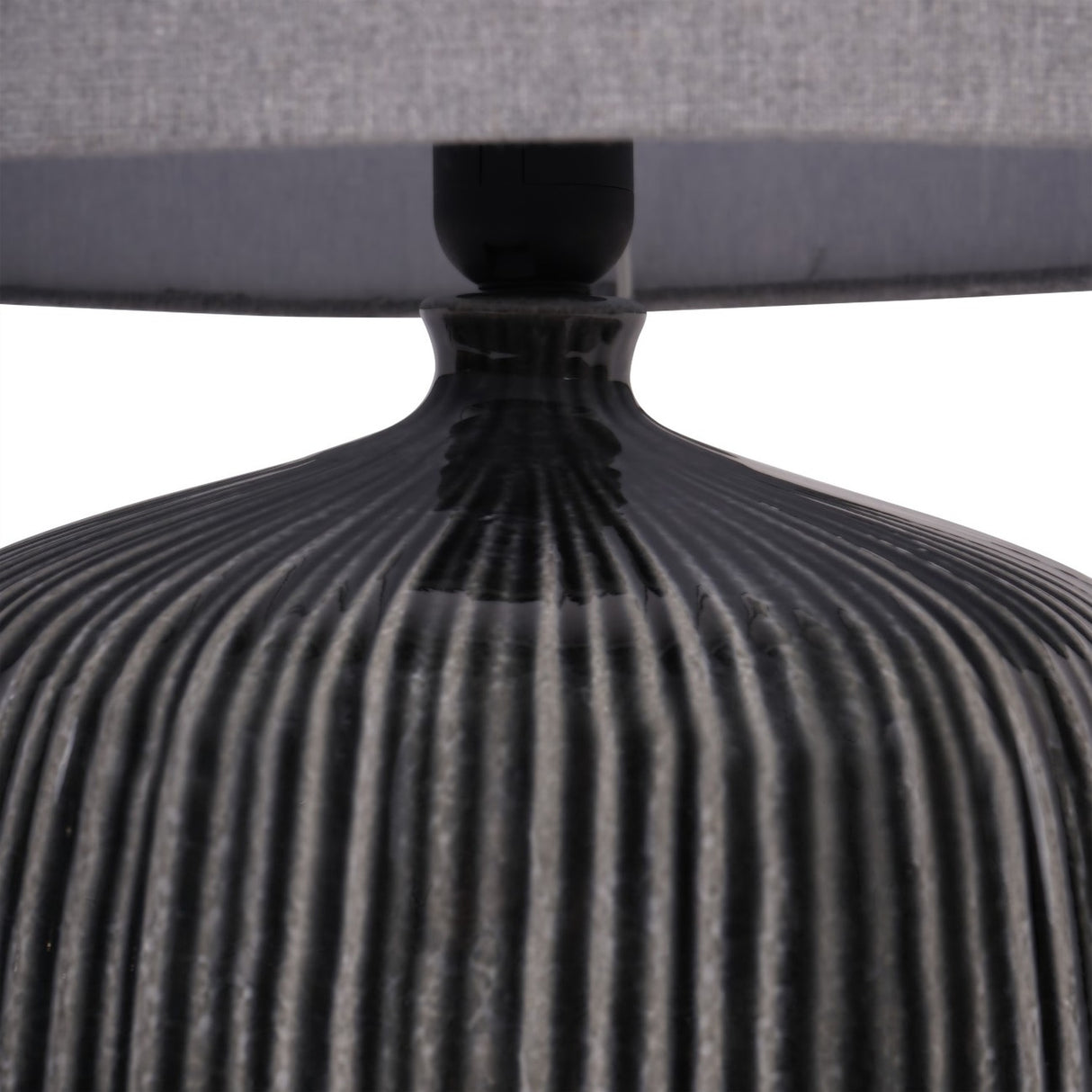 Close-up of Libra Interiors Ribbed Ceramic Table Lamp in charcoal, showing the glazed vertical ribbing on the rounded base beneath a grey fabric drum shade.