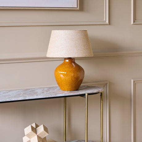 Libra Interiors glazed ceramic table lamp with a rounded terracotta brown urn base and natural hessian shade, styled on a marble console table.