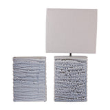 Libra Interiors Rippled Ceramic Rectangular Vase in blue reactive glaze shown beside a linen-shaded table lamp with a matching textured ceramic base.