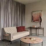 Libra Interiors Twisting Leaf aluminium abstract sculpture in bronze on a marble console table beside an abstract painting in a neutral living room.