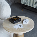 Libra Interiors Ace of Spades black resin card game box with gold motif on a round travertine side table, deck fanned beside it in a living room.