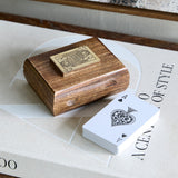 Libra Interiors Mango Wood Brass Inlay Card Game box with Queen of Spades lid motif, shown beside a deck of cards on a style book.