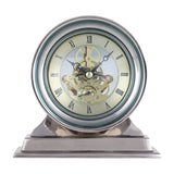 Libra Interiors Skeleton mantel clock with polished nickel case, stepped base, domed glass lens, exposed gold cogs and cream Roman numeral dial.