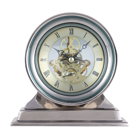 Libra Interiors Skeleton mantel clock with polished nickel case, stepped base, domed glass lens, exposed gold cogs and cream Roman numeral dial.