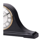 Close-up side view of the Libra Interiors matt black Roman numeral mantel clock, showing its curved humped profile, stepped base and gold bezel edge.