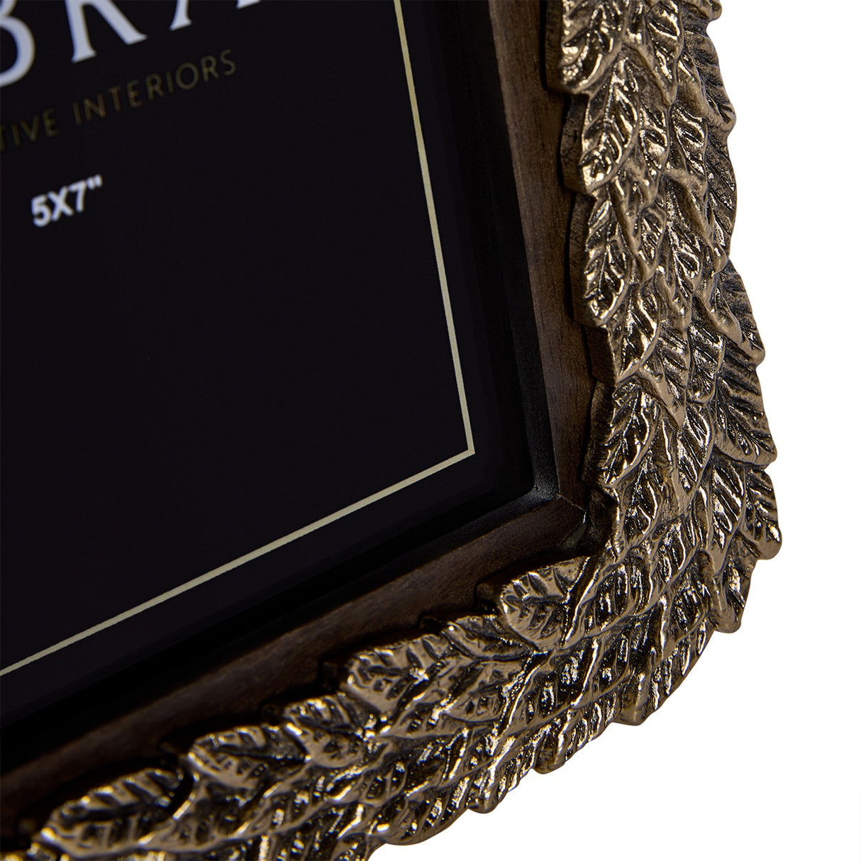 Close-up of the Libra Interiors Antiqued Gold Leaf Photo Frame corner, showing the cast aluminium raised leaf border and dark wooden inner frame.