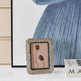 Libra Interiors Antiqued Leaf Aluminium Photo Frame in silver, displayed on a marble surface beside blue artwork and Matisse books in a living room setting.