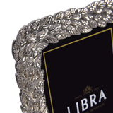 Close-up corner detail of Libra Interiors Antiqued Leaf aluminium photo frame in silver, showing raised botanical leaf motif with antiqued pewter finish.