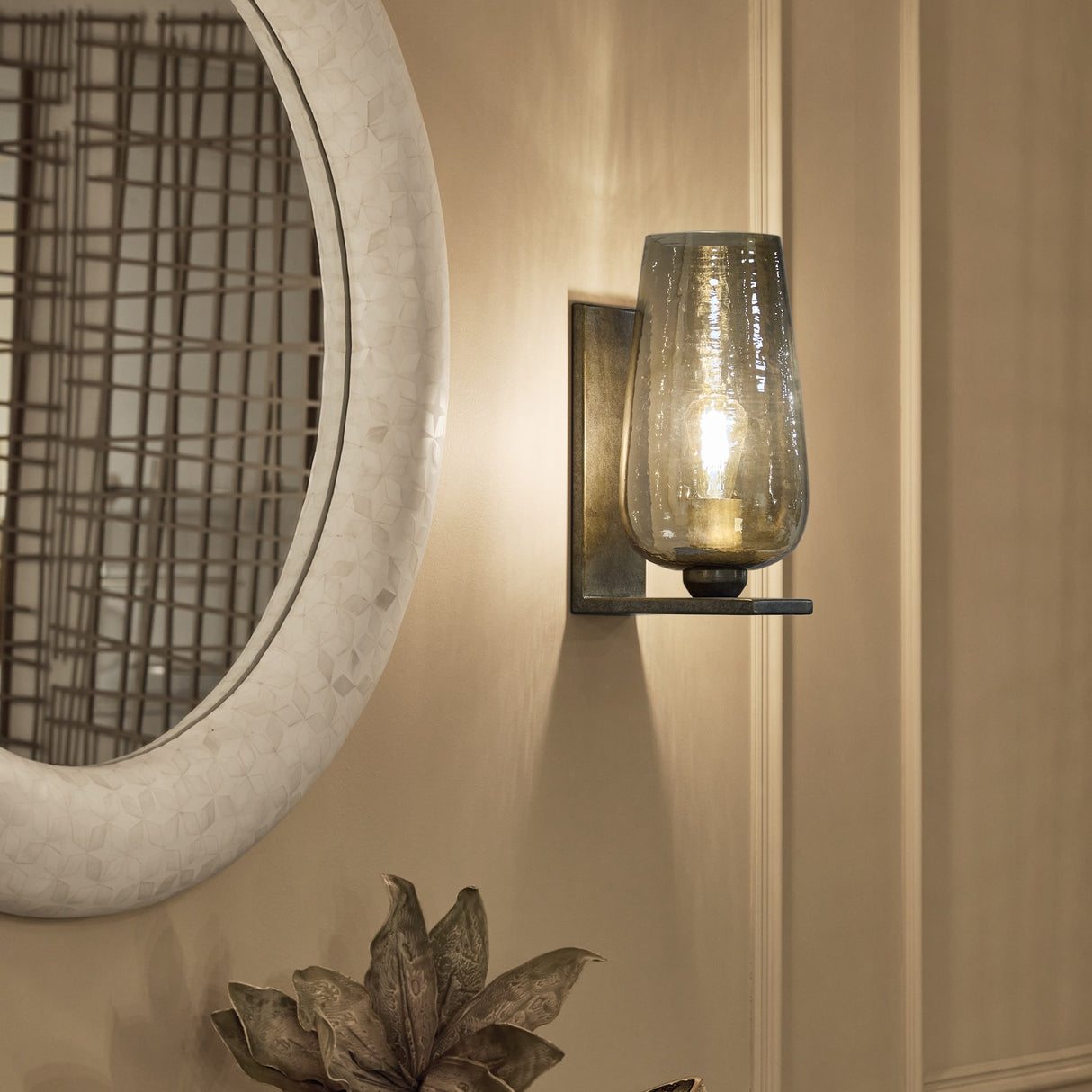 Libra Interiors Hammered Glass Tulip Wall Light in brown with tulip-shaped lustred glass shade and aged gold backplate, mounted beside a round mosaic mirror.