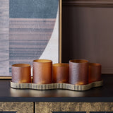 Libra Interiors Hammered Glass 5 Light Amber Lantern with amber votives at stepped heights on a ribbed aged gold base, styled on a dark console.